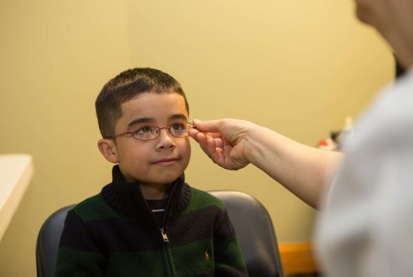 Optician fitting glasses to a student